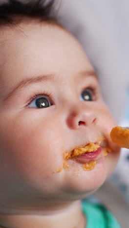 nice kid eating porridge from spoon. adorable toddler sticks out tongue and waves his hands. close up. vertical video
