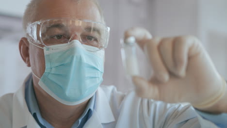 la mano del médico sostiene una jeringa y una botella azul de vacuna en el hospital. conceptos de salud y medicina. el médico dibuja la vacuna en la jeringa vial inyección de ampola de coronavirus covid-19. imágenes de alta calidad 4k