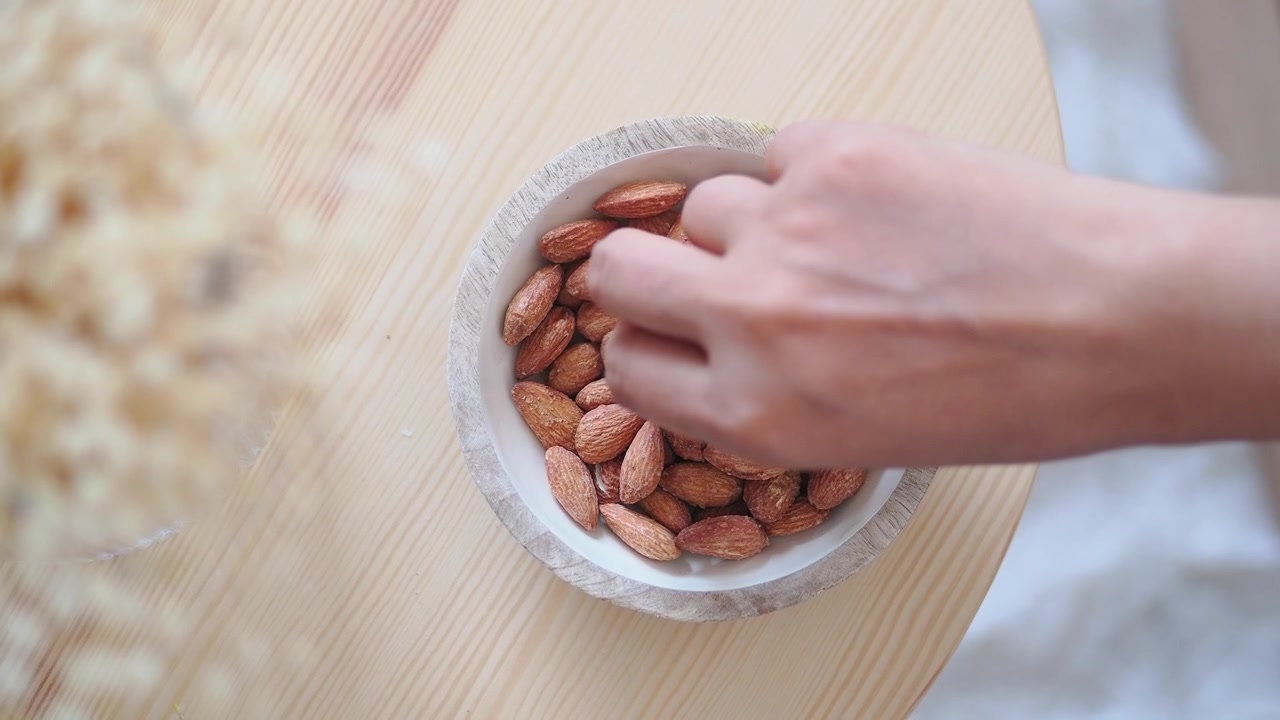 Hånd plukker mandler fra en treskål