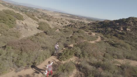 drone chasing downhill dirt bike rider fast turning and jumping off ramps with tricks