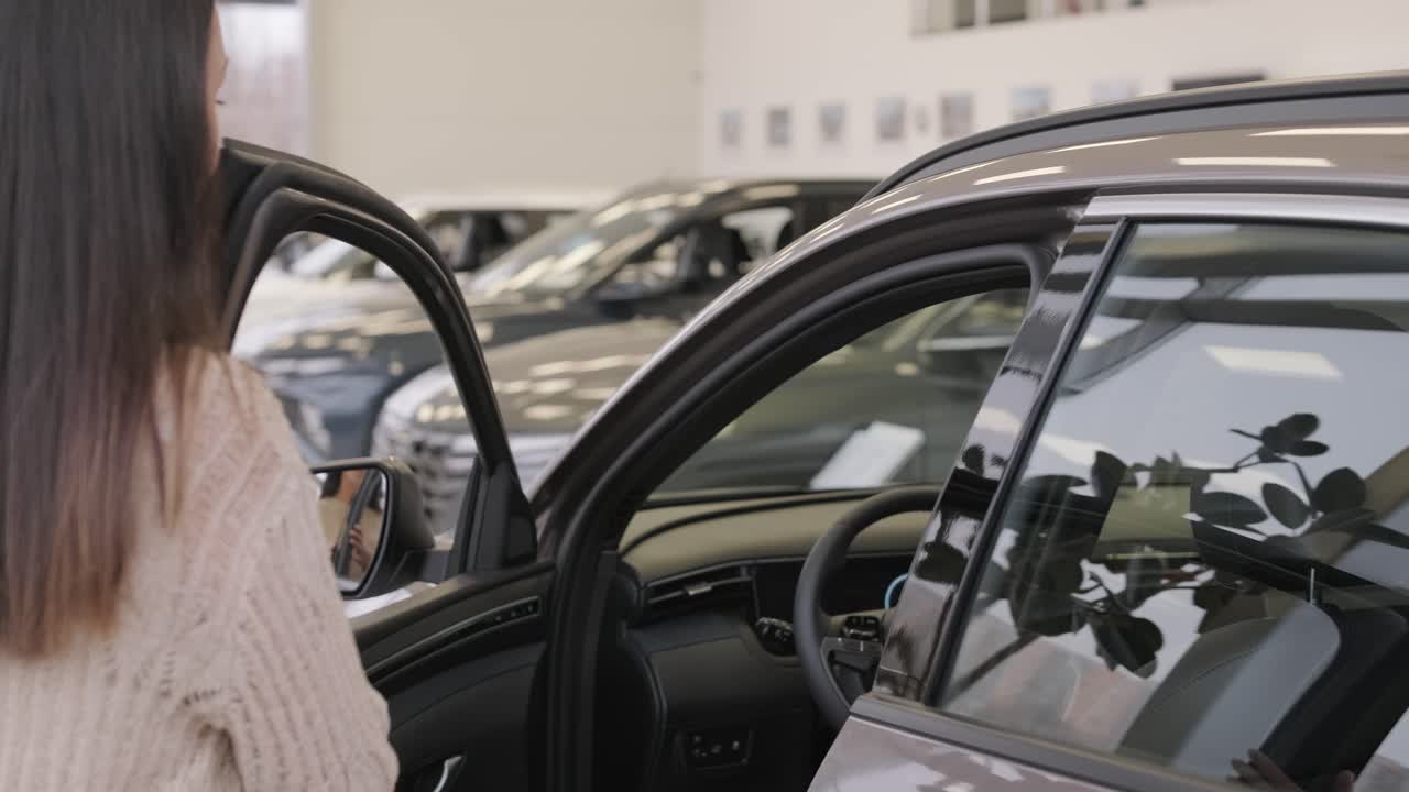 mujer eligiendo un coche en una sala de exposición de automóviles