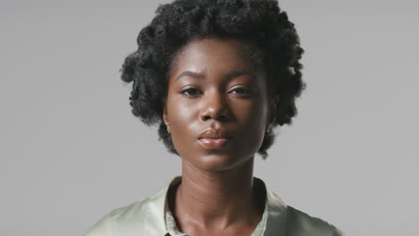 Studio-Portrait-Of-Serious-Young-Businesswoman-Turning-To-Face-Camera-Against-Plain-Background