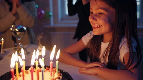 happy girl celebrating birthday with lit candles on cake
