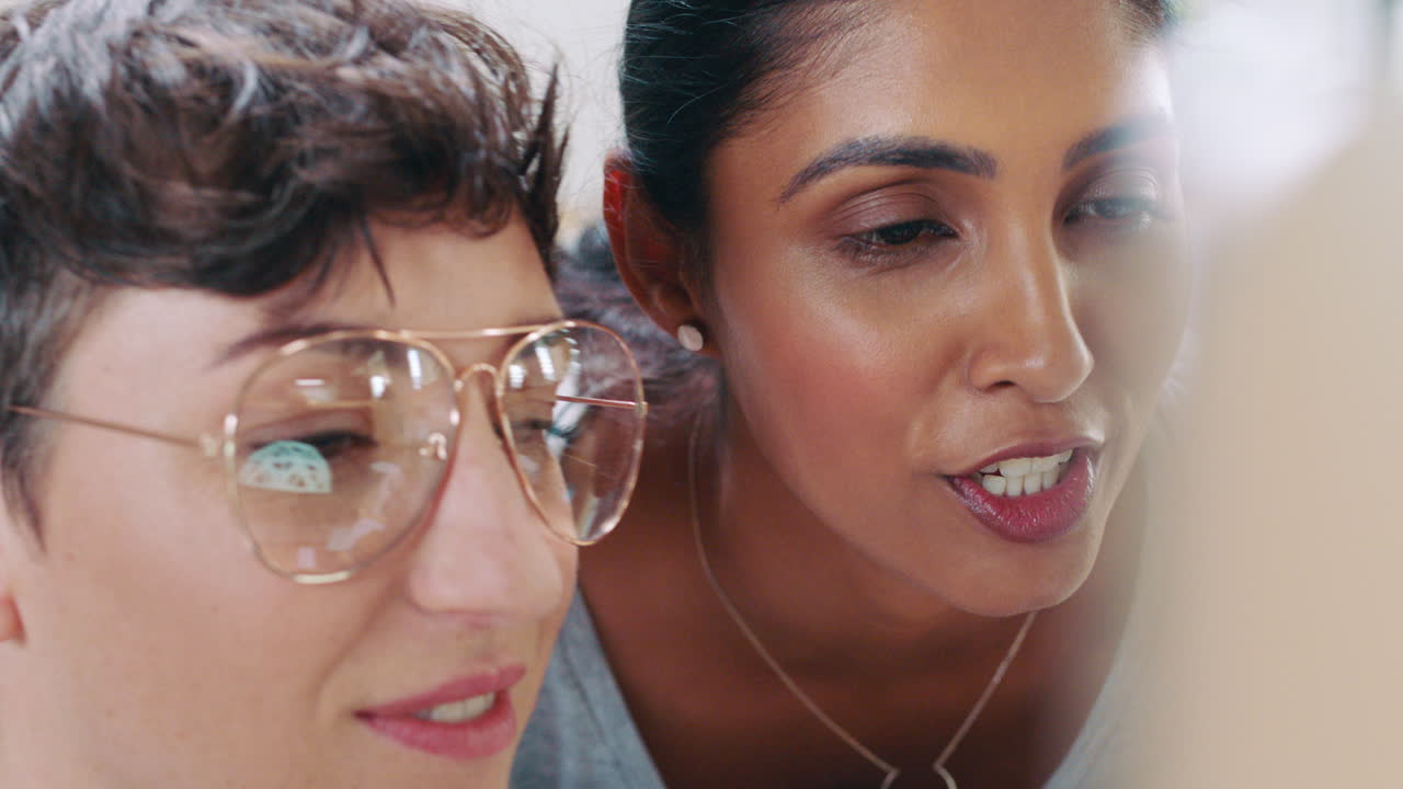 Two Female Coworkers Collaborating and Discussing Work in Office