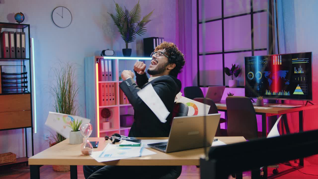 Likable cheerful contented successful bearded asian office manager rejoycing from good made work and scattering papers over his head in evening office