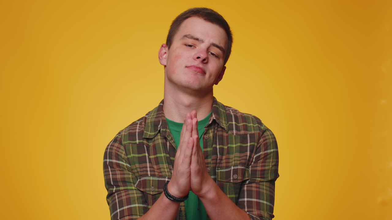 트렌디한 젊은 성인 남자가 기도하고, 위를 올려다보며 소원을 하고, 하나님께 도움을 요청하고, 사과하고 있습니다.