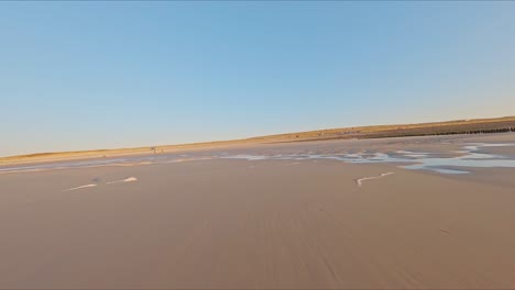 Hermosa-Toma-De-Drones-Fpv-De-Alta-Velocidad-Volando-Sobre-Las-Olas-De-Una-Playa-Durante-Una-Puesta-De-Sol-Sin-Nubes