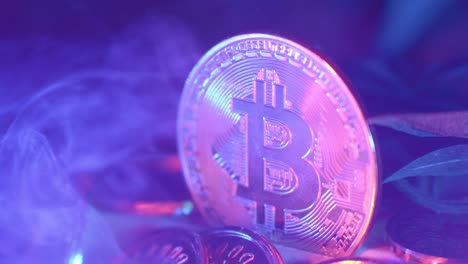close-up shot of a shiny golden bitcoin under led lights with smoke passing