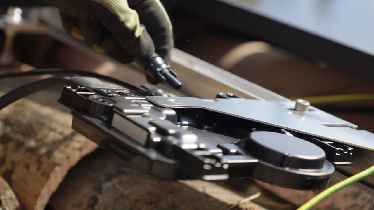 gloved hand installs wiring on metallic solar panel mechanism close up