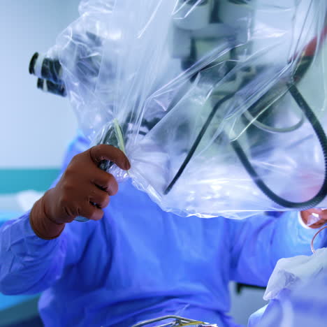 uniformed neurosurgeon moves the microscope. doctor sets the equipment above the patient before the surgery.