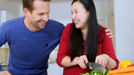 woman cutting vegetable while interacting with man in kitchen 4k