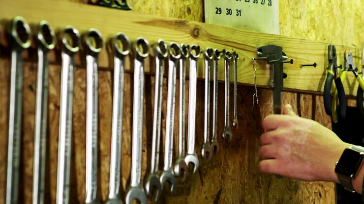 Human hand takes vernier caliper from wall. Set of mechanical tools in garage