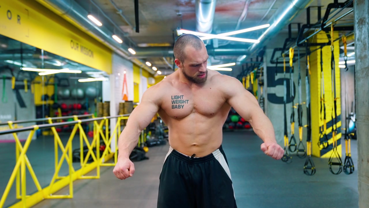 Uomo muscoloso che flette i muscoli del petto e delle braccia in una palestra moderna