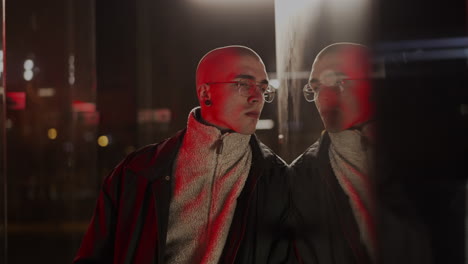 urban portrait of a man reflected in a window at night with red light