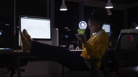 mujer de negocios bebiendo café y trabajando en una oficina moderna por la noche