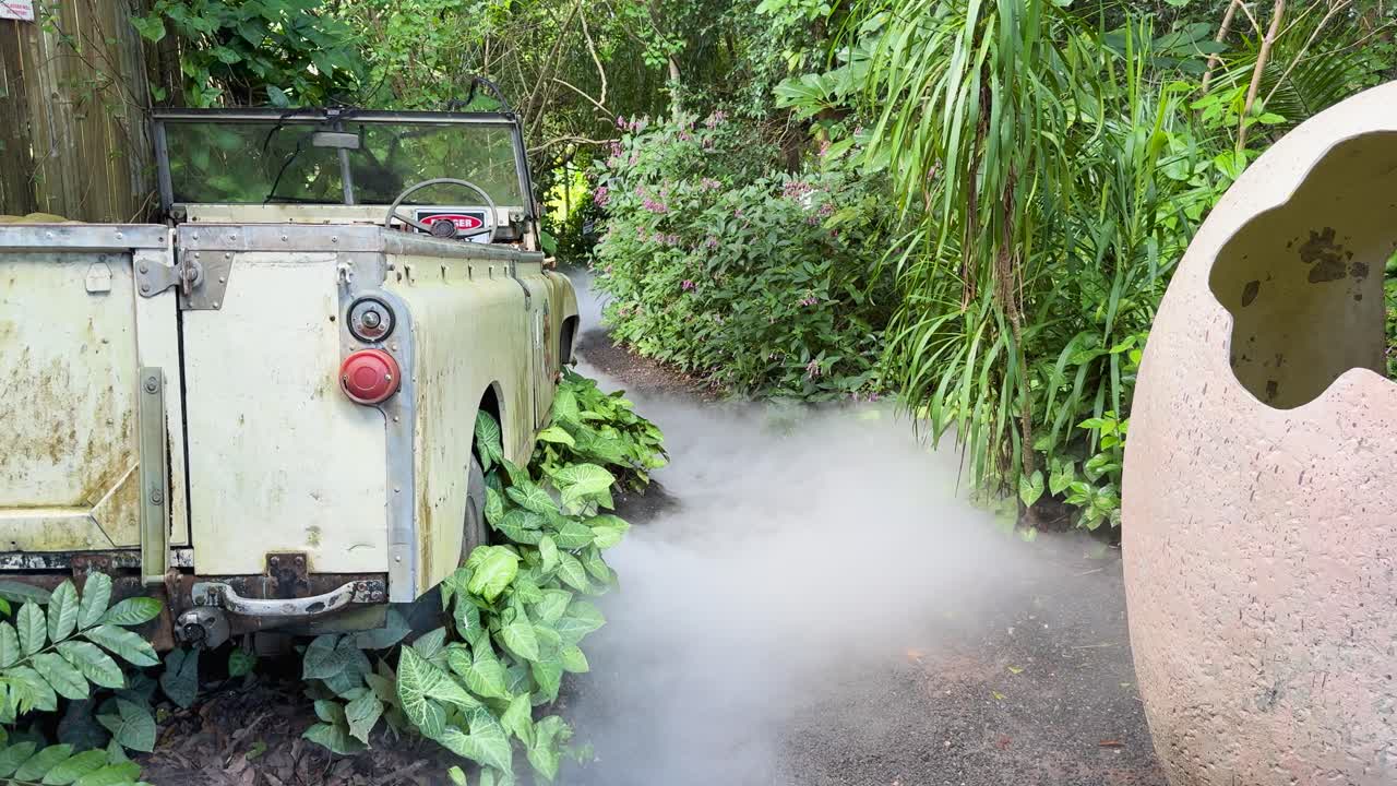 Static shot of vintage jeep, large dinosaur egg, fog effects, dense greenery, natural daylight