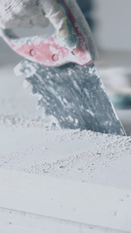 professional worker in gloves holds big saw and cuts actively large grey gypsum plasterboard on stand close view