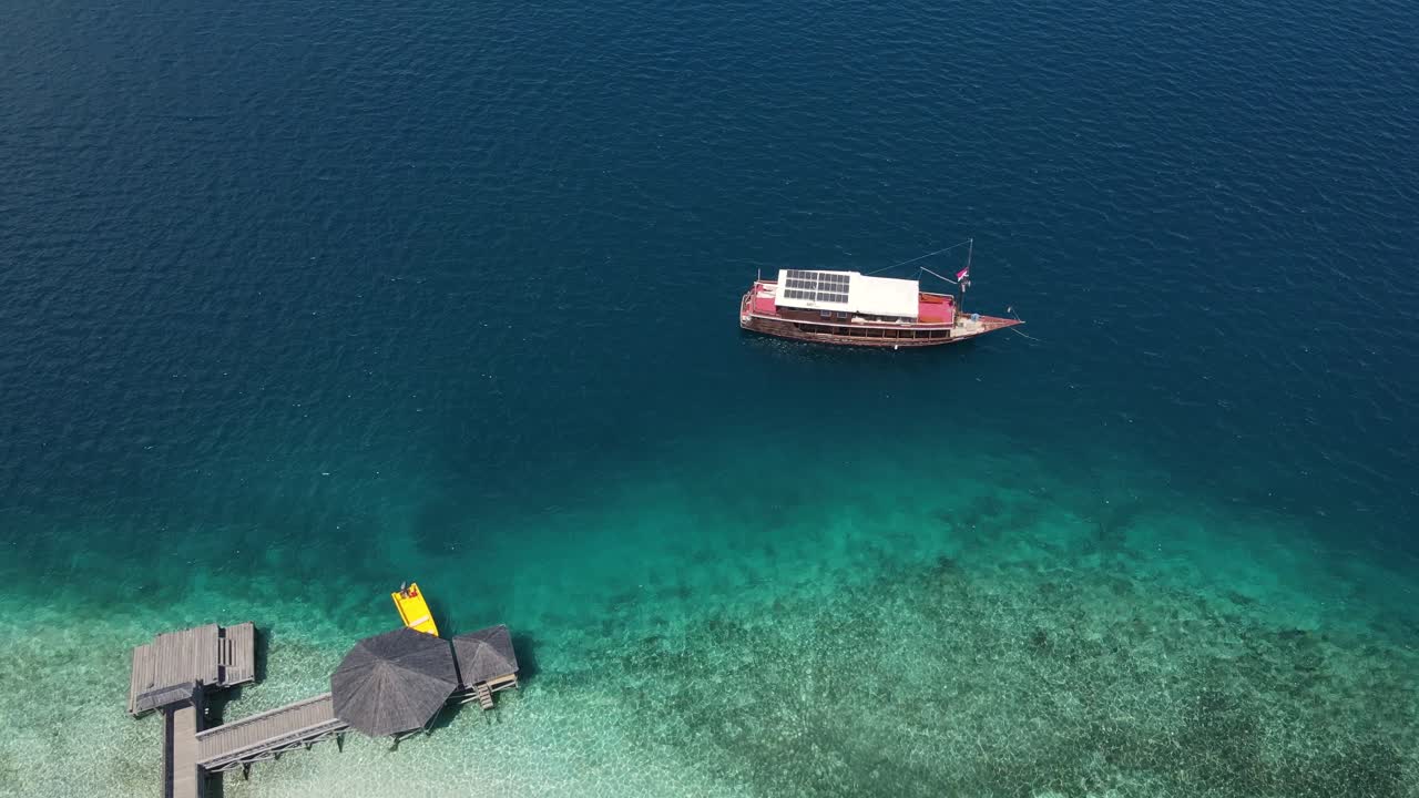 인도네시아 코모도 섬의 부두와 백사장 옆에 태양광 패널이 있는 보트 공중, 조감도, 드론 샷