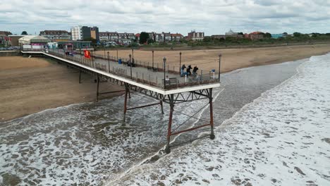 Typischer-Englischer-Badeort,-Aufgenommen-Mit-Einer-Drohne,-Die-Einen-Hohen-Luftbildpunkt-Bietet,-Der-Einen-Weiten-Sandstrand-Mit-Einem-Pier-Und-Tosenden-Wellen-Zeigt-3