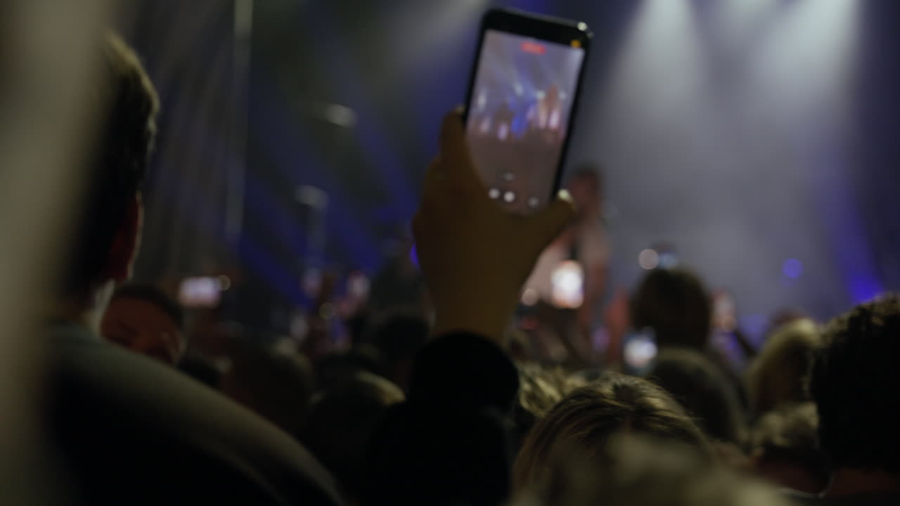 Persona che registra un concerto dal vivo con lo smartphone tra la folla