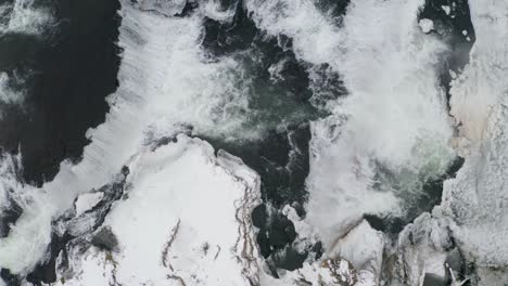 aerial tilt up shot of vast reykjafoss waterfall during snowy day in iceland