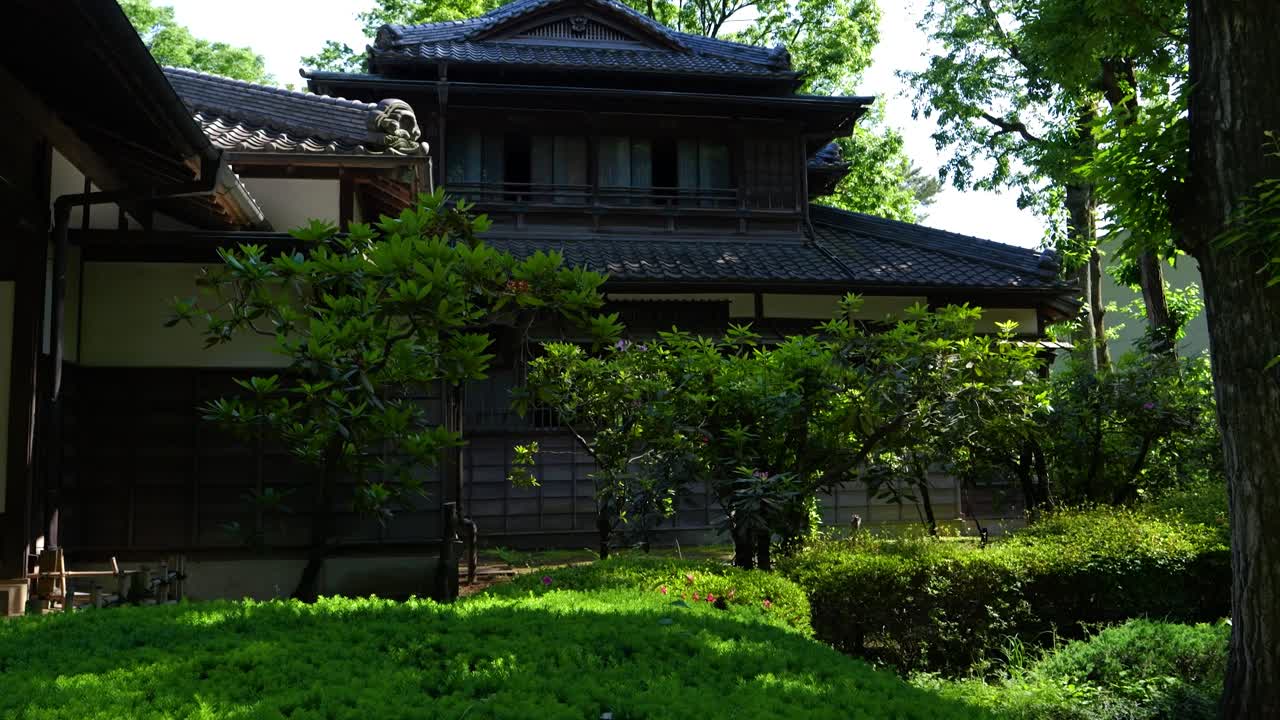 초록색으로 둘러싸인 전통적인 일본 목조 집 위에 느린 움직임으로 기울어