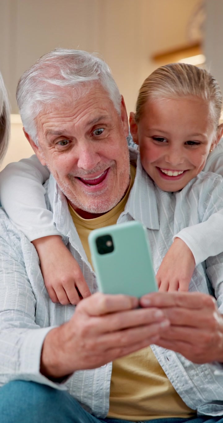 Bedstefar og barnebarn kigger på smartphone sammen