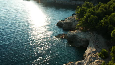 tourists on the edge of cliff of seagull’s rocks beach on a sunny summer day in stoja, pula, croatia