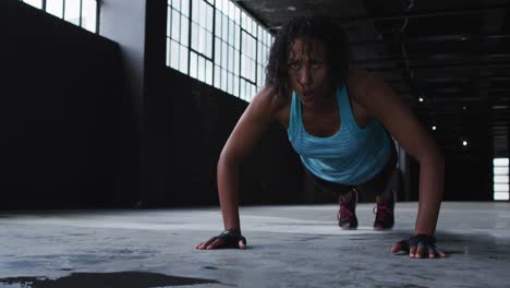 mujer afroamericana haciendo flexiones en un edificio urbano vacío