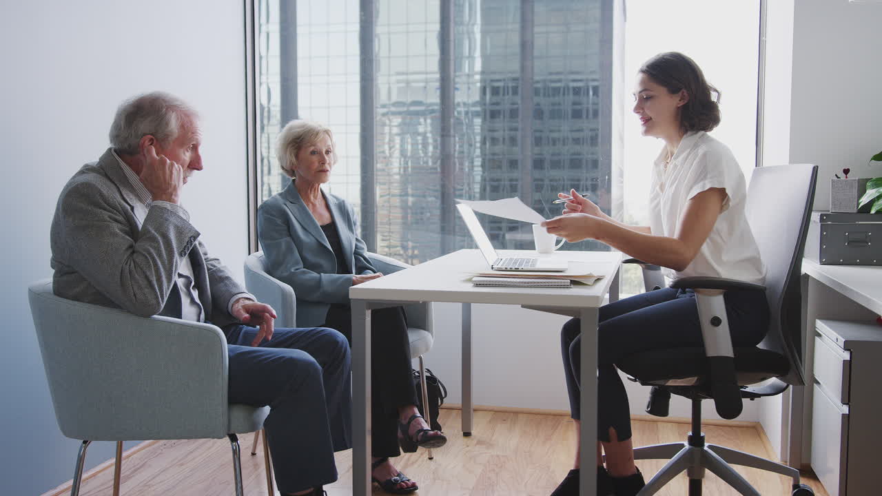 pareja de alto rango firmando un documento en una reunión con una asesora financiera en la oficina