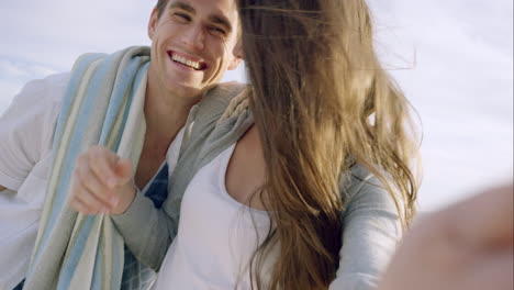 happy couple taking selfie on beach at sunset using phone smiling and spinning enjoying nature and lifestyle on vacation