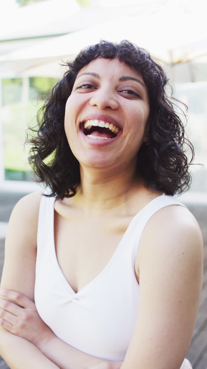 retrato vertical de video de una mujer bi-racial feliz riendo a la cámara