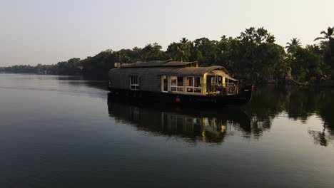 tranquil view of a luxury houseboat sailing in the tropical lake of kerala in alleppey, india