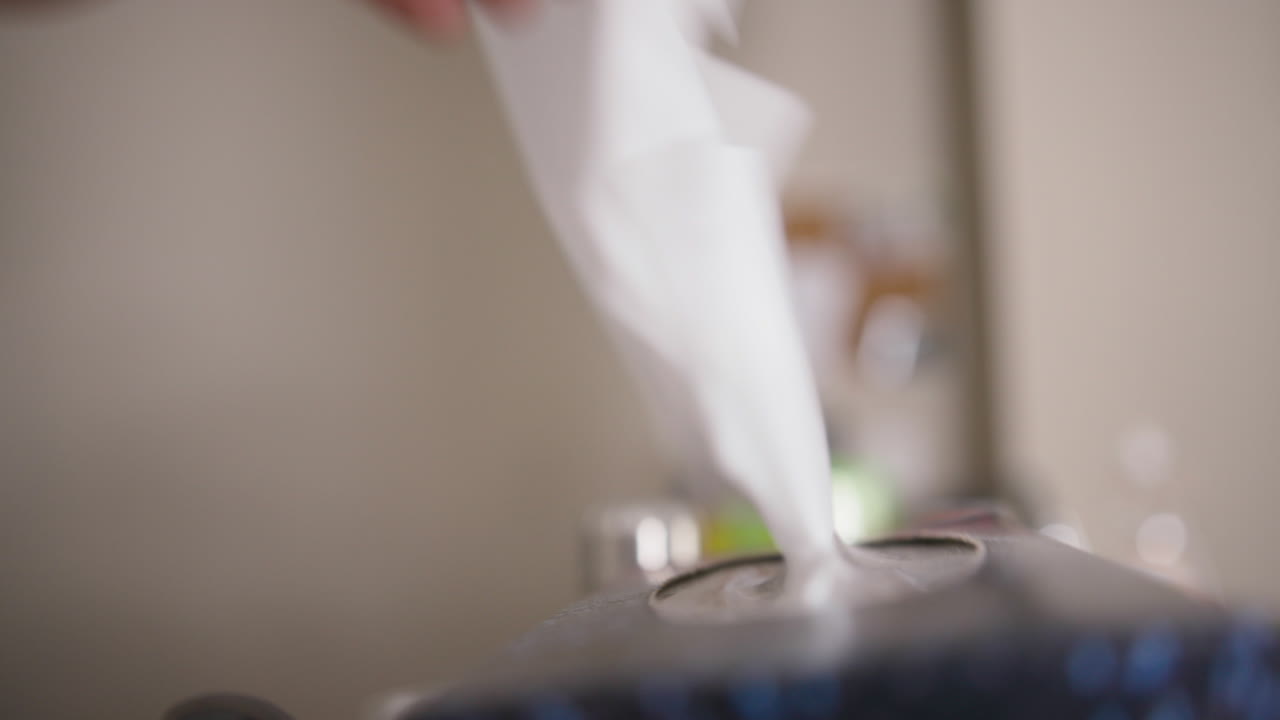 primer plano de una mano tirando de un pañuelo de una caja de pañuelos