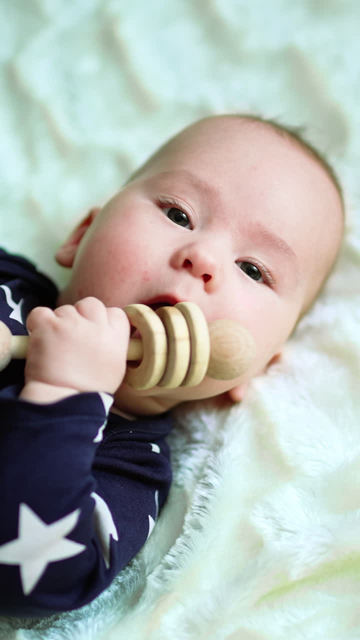 Playful child laying on a bed. Baby playing lying on a blanket. Vertical video