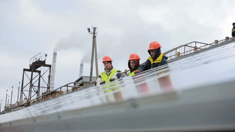 vinnitsa, ukraine - november 2017: workers in uniform and hardhat install solar panels on solar farm