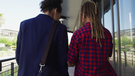 Two-diverse-male-friends-walking-in-the-street-looking-at-smartphone