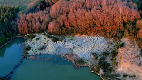 Aerial-View-Of-Low-Level-Lake-Pond-With-Sun-Lit-Autumnal-Trees-In-Rural-Galacia