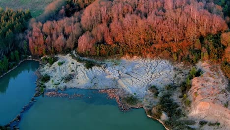 aerial view of low level lake pond with sun lit autumnal trees in rural galacia