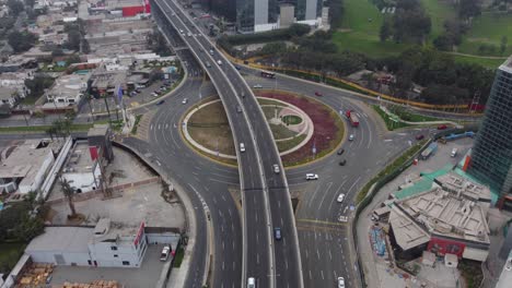imágenes de drones del paso elevado recién construido en lima, perú, encima de una rotonda llamada "óvalo monitor huascar", se pueden ver autos circulando por calles con poco tráfico en un día nublado