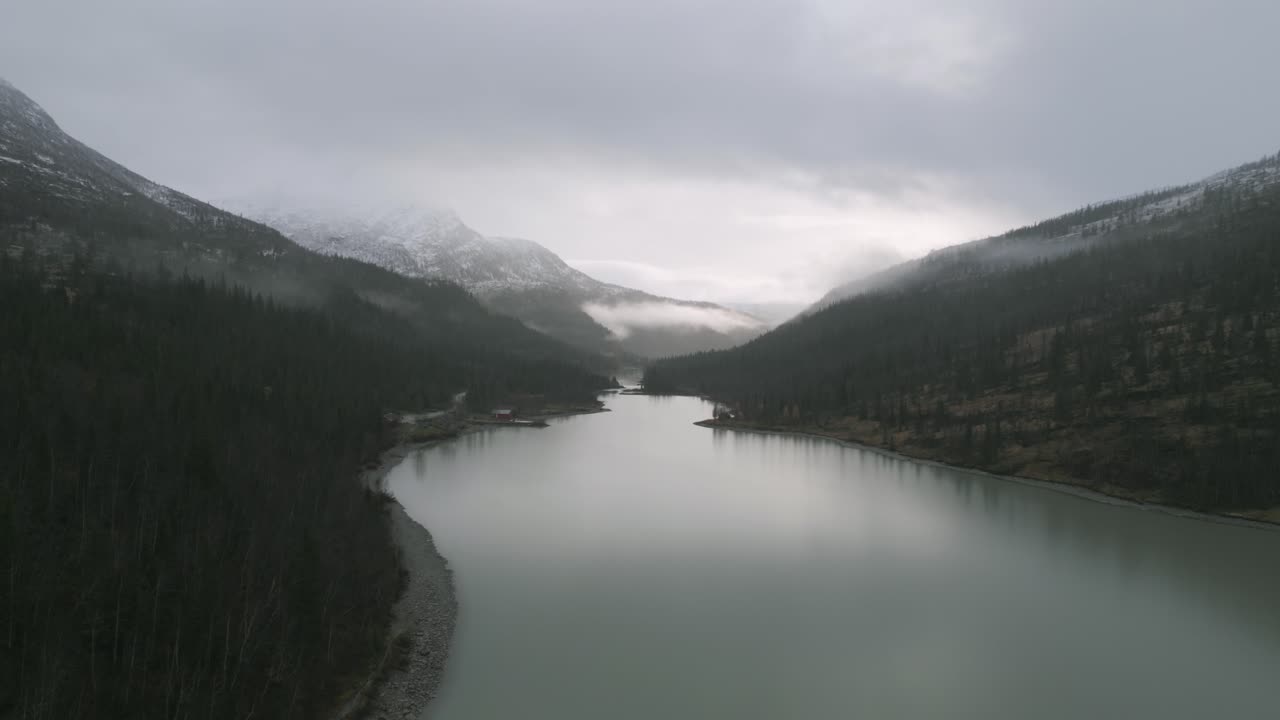 Misty lake Svartisvatnet, Norway, surrounded by snow-dusted mountains, cloudy skies above
