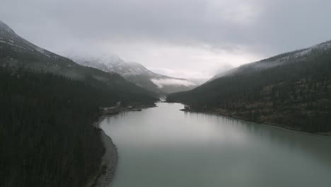 Misty-lake-Svartisvatnet,-Norway,-surrounded-by-snow-dusted-mountains,-cloudy-skies-above