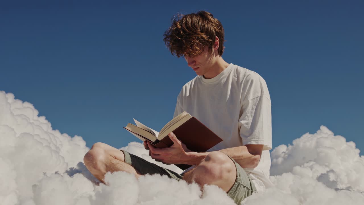 Un concept video surreale con un giovane uomo che legge sulle nuvole