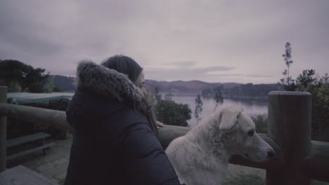 HD-of-a-woman-and-her-dog-outdoog-house-in-front-of-a-lake