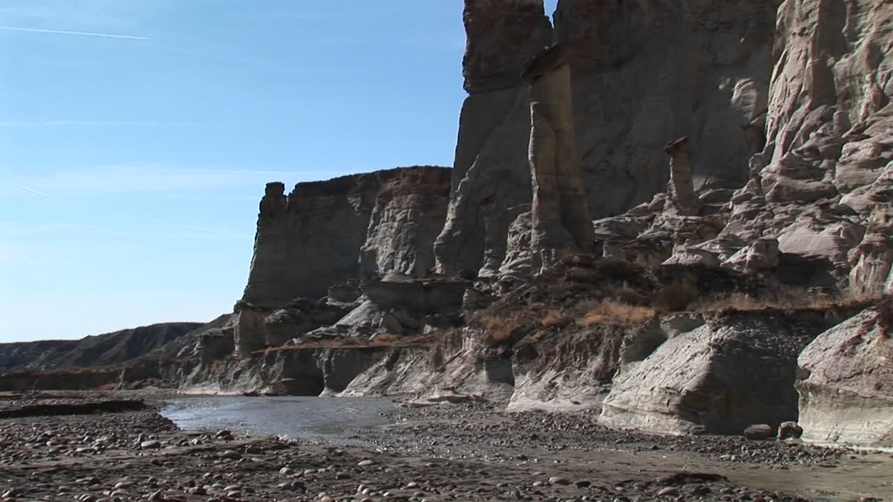 средний снимок ручья в пустыне, протекающего у основания скальной стены