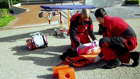 paramedics putting injured girl onto a backboard