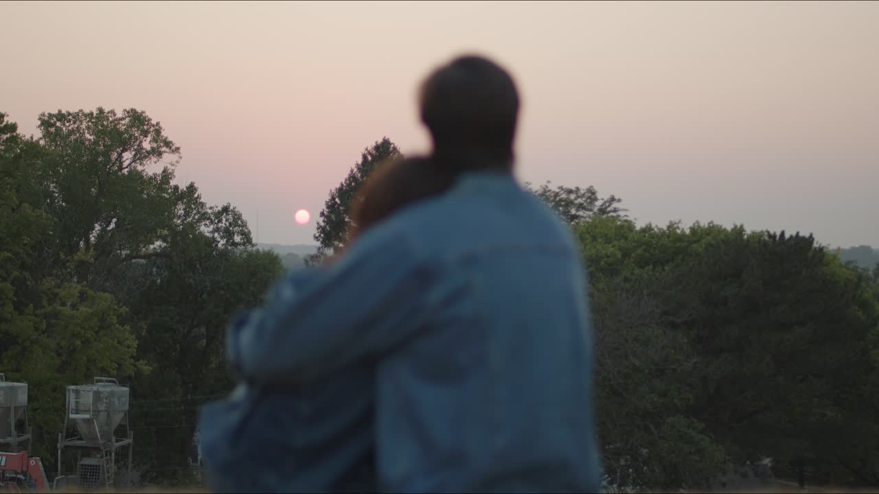 Couple sitting together watch the sunset at a park in late summer