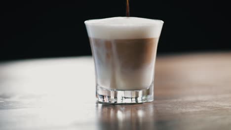 Nahaufnahme-Von-Heißem-Kaffee,-Der-In-Ein-Glas-Mit-Heißer-Milch-Und-Schaum-Gegossen-Wird