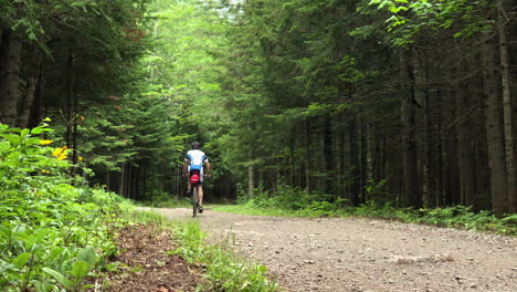 young male adult biking on a gravel road by himself on a summer day