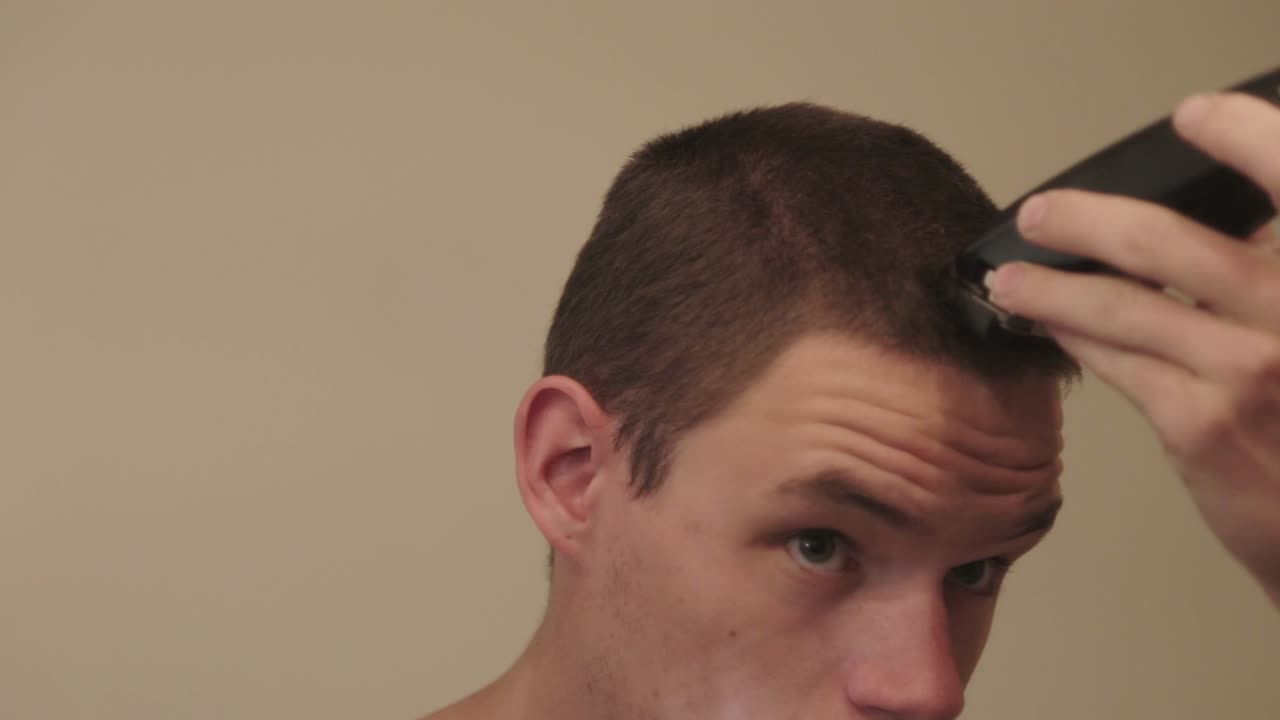 흰색 배경의 전기 면도기로 머리를 자르는 남자 - 클로즈업 샷